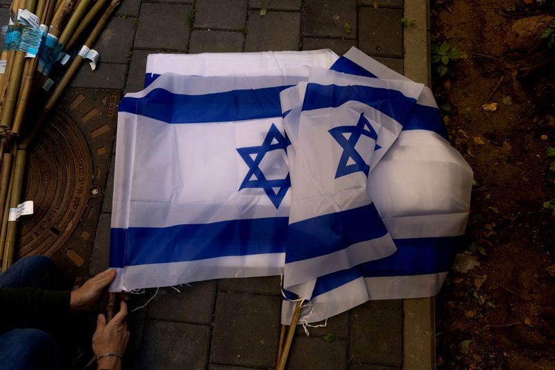 FOTO DE ARCHIVO: Un voluntario junta banderas israelíes en preparación para las protestas contra la reforma judicial del país frente a un bloque de apartamentos en Tel Aviv, Israel, el 30 de marzo de 2023. REUTERS/Ronen Zvulun