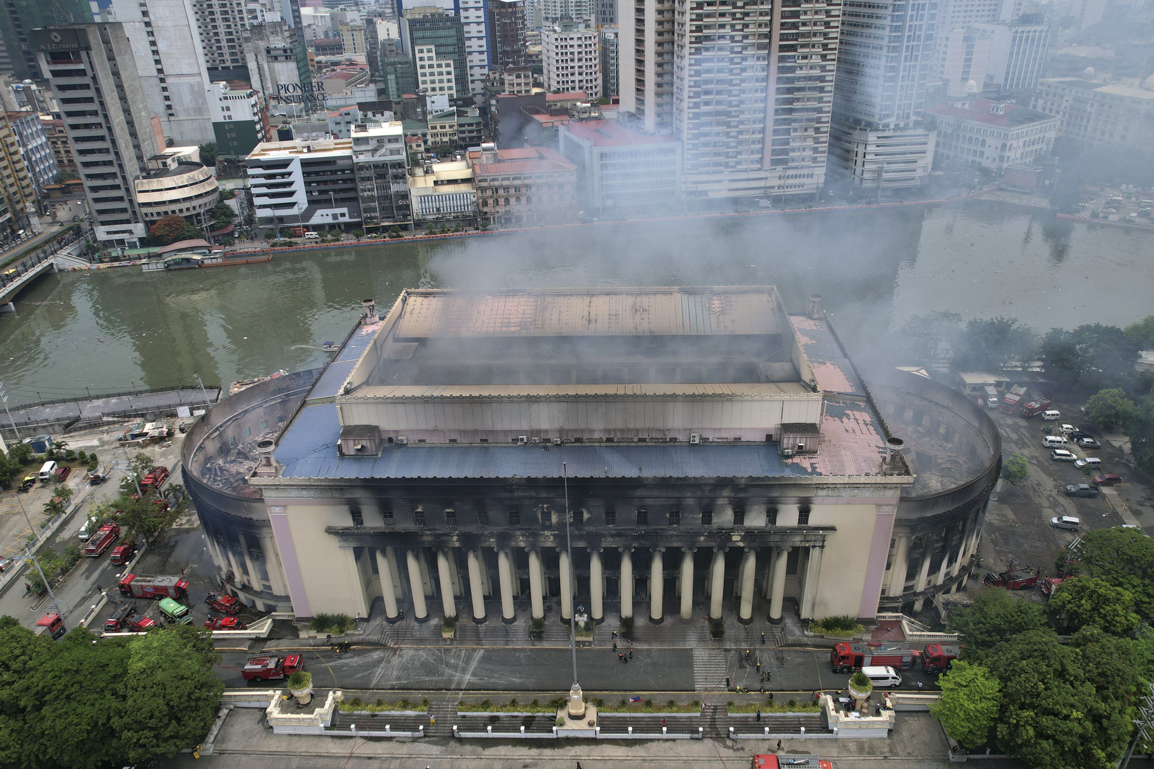 El humo sale de la Oficina Postal Central de Manila, aún humeante tras un incendio el lunes 22 de 2023 en Manila, Filipinas. Un enorme incendio se extendió por el edificio histórico de correos durante la noche. (AP Foto/Aaron Favila)