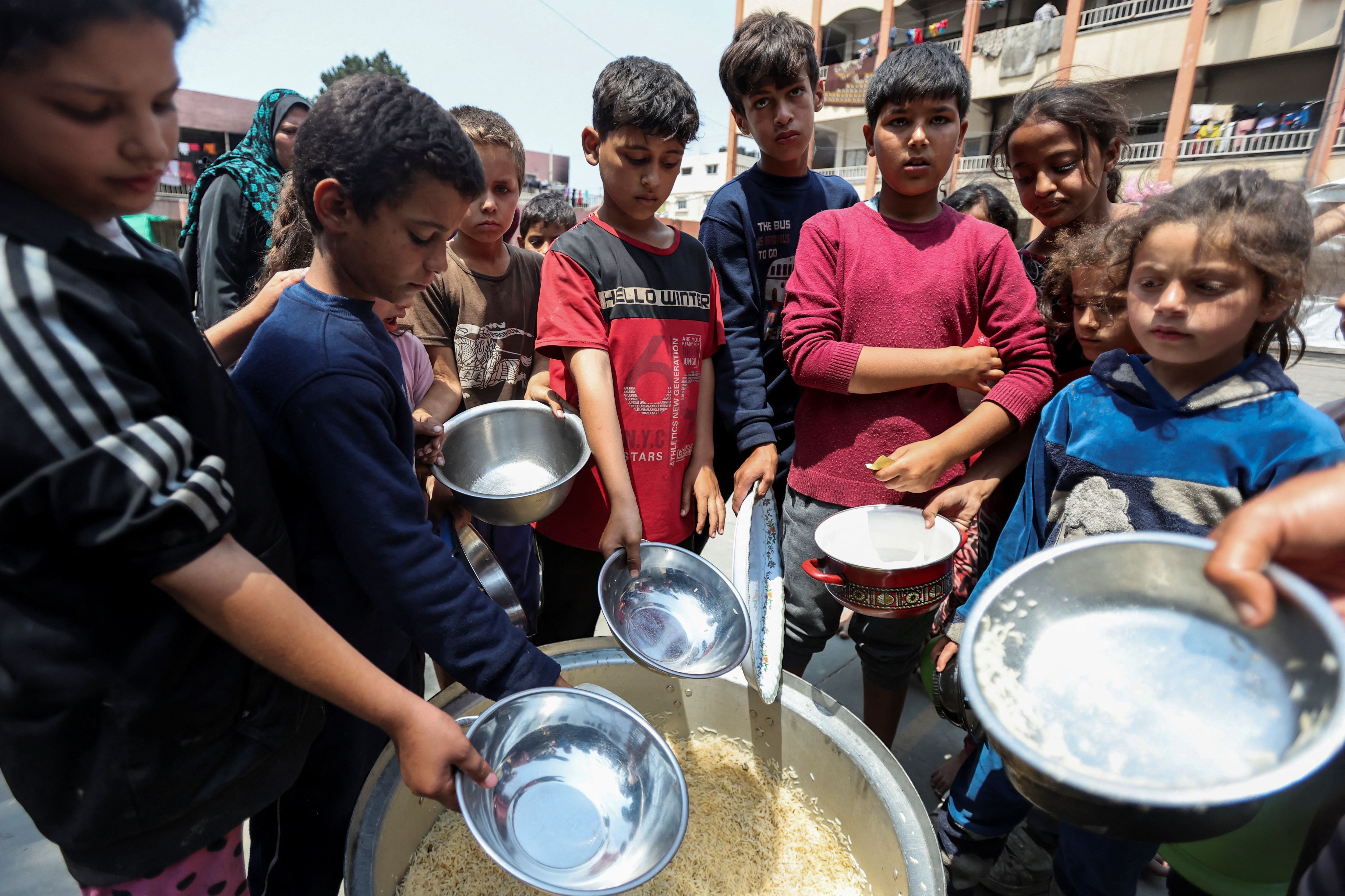 Los palestinos se reúnen para recibir comidas cocinadas por World Central Kitchen (WCK) después de que la organización benéfica reanudó sus operaciones, en una escuela que alberga a personas desplazadas, en medio del conflicto en curso entre Israel y Hamás, en Deir Al-Balah, en el centro de la Franja de Gaza, el 1 de mayo de 2024. REUTERS/Ramadán Abed