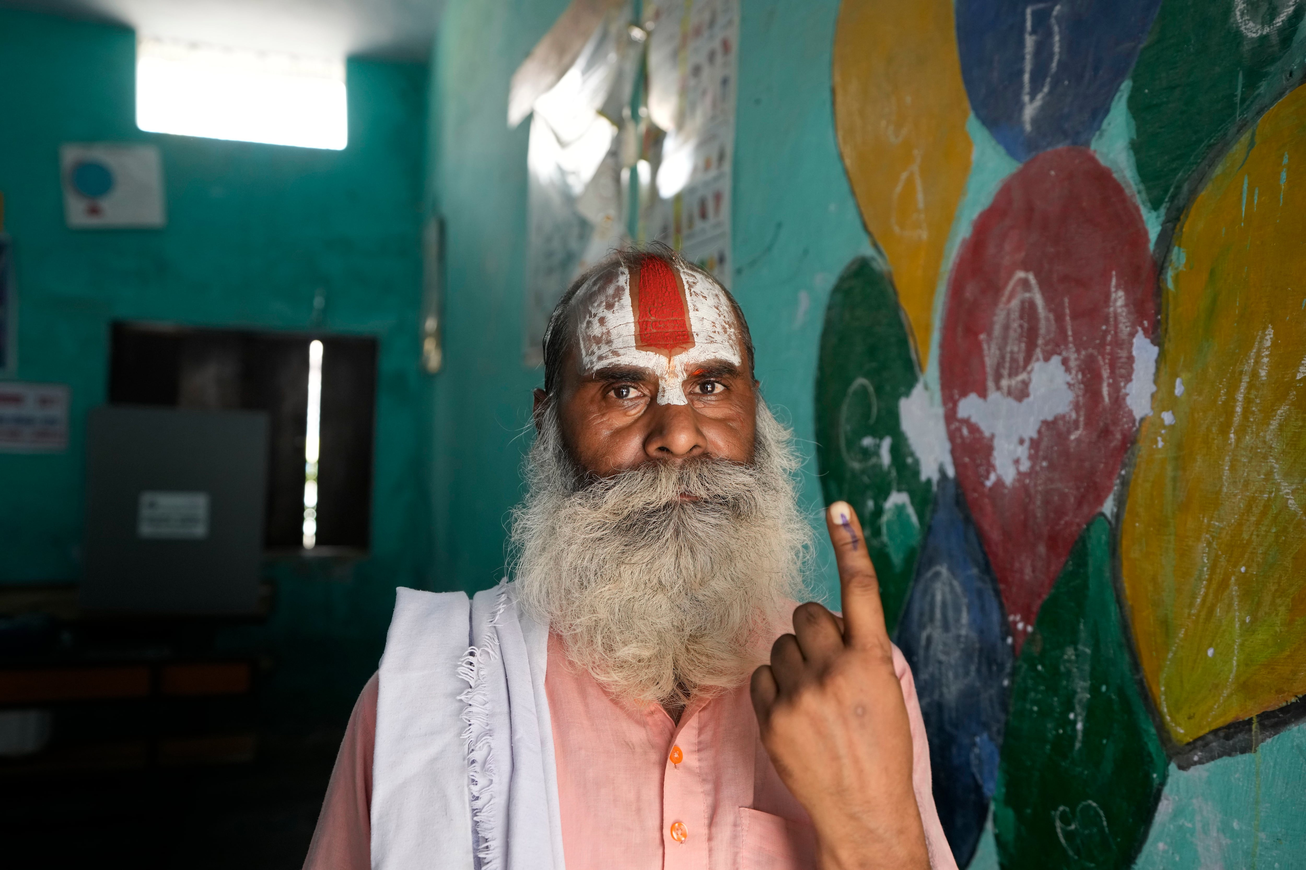 Un religioso hindú indio muestra su dedo marcado con tinta indeleble tras votar en la quinta ronda de unas elecciones nacionales de varias fases ante un centro electoral en Ayodhya, India, el lunes 20 de mayo de 2024. (AP Foto/Rajesh Kumar Singh)