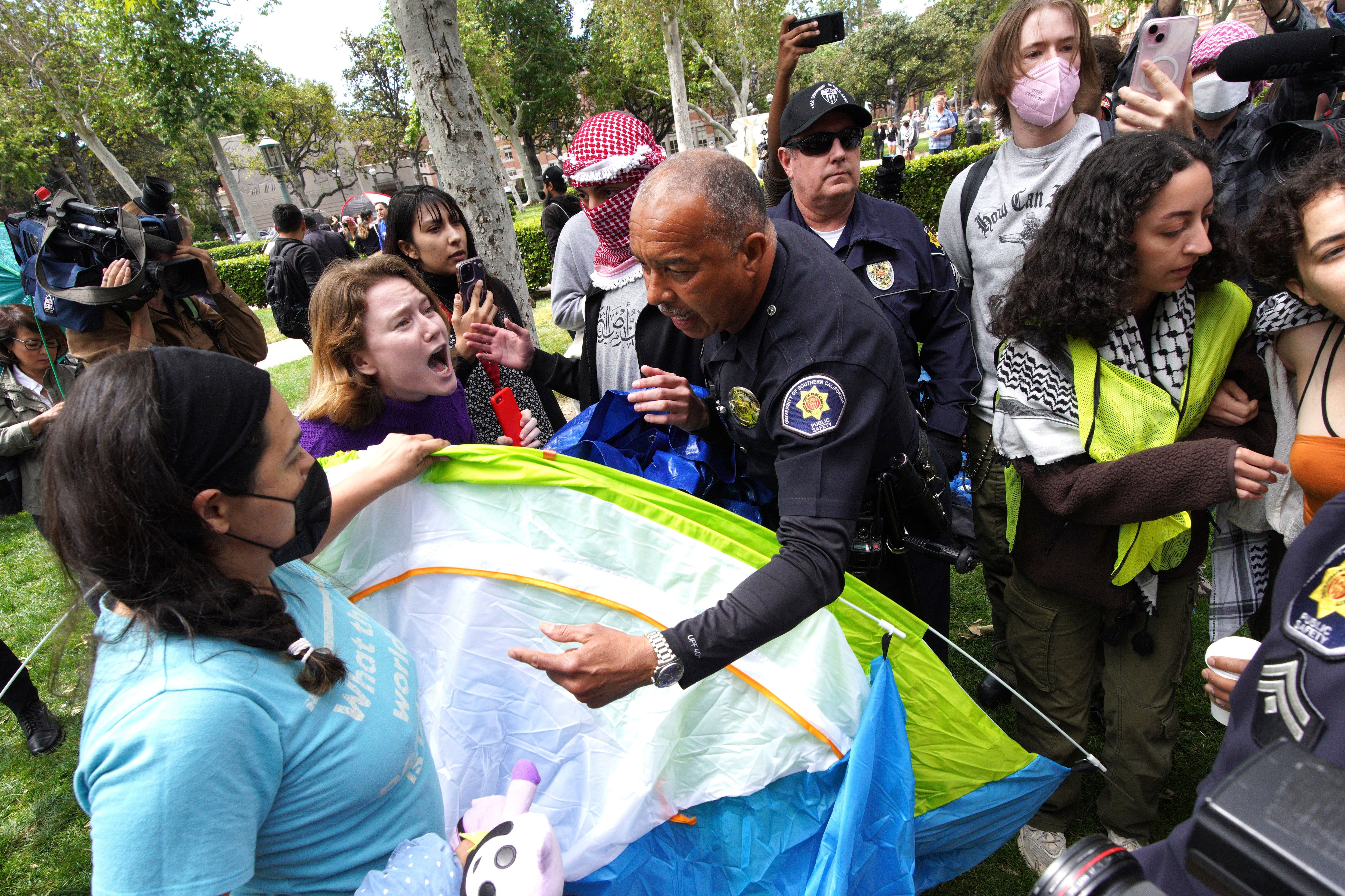 Manifestantes de la Universidad del Sur de California discuten con agentes de seguridad mientras intentan retirar tiendas de campaña en el Parque de los Exalumnos durante una protesta en favor de los palestinos (AP Foto/Richard Vogel)