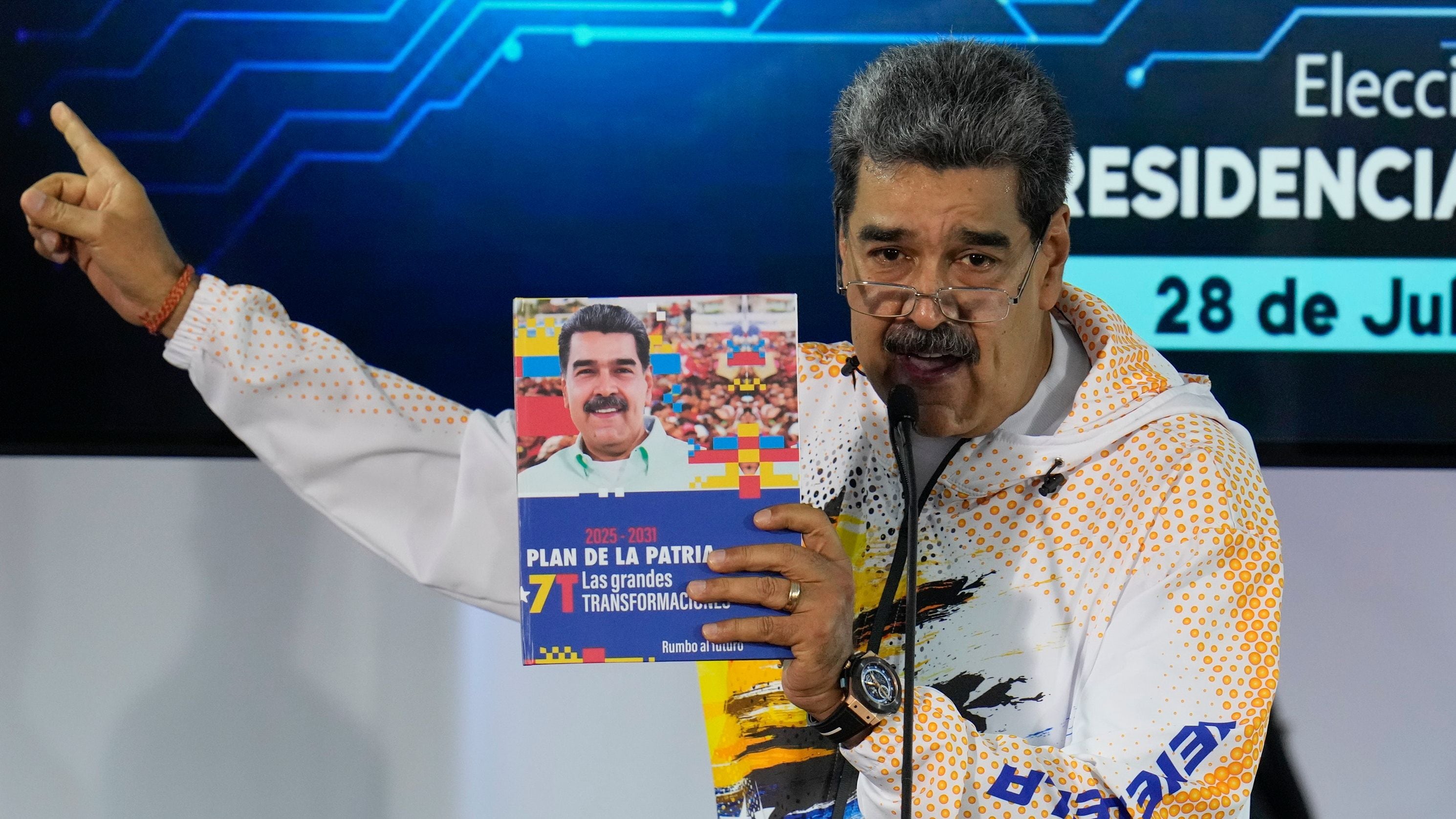 Nicolás Maduro sostiene un libro con su fotografía mientras habla en la Comisión Nacional Electoral (AP Foto/Ariana Cubillos, Archivo)