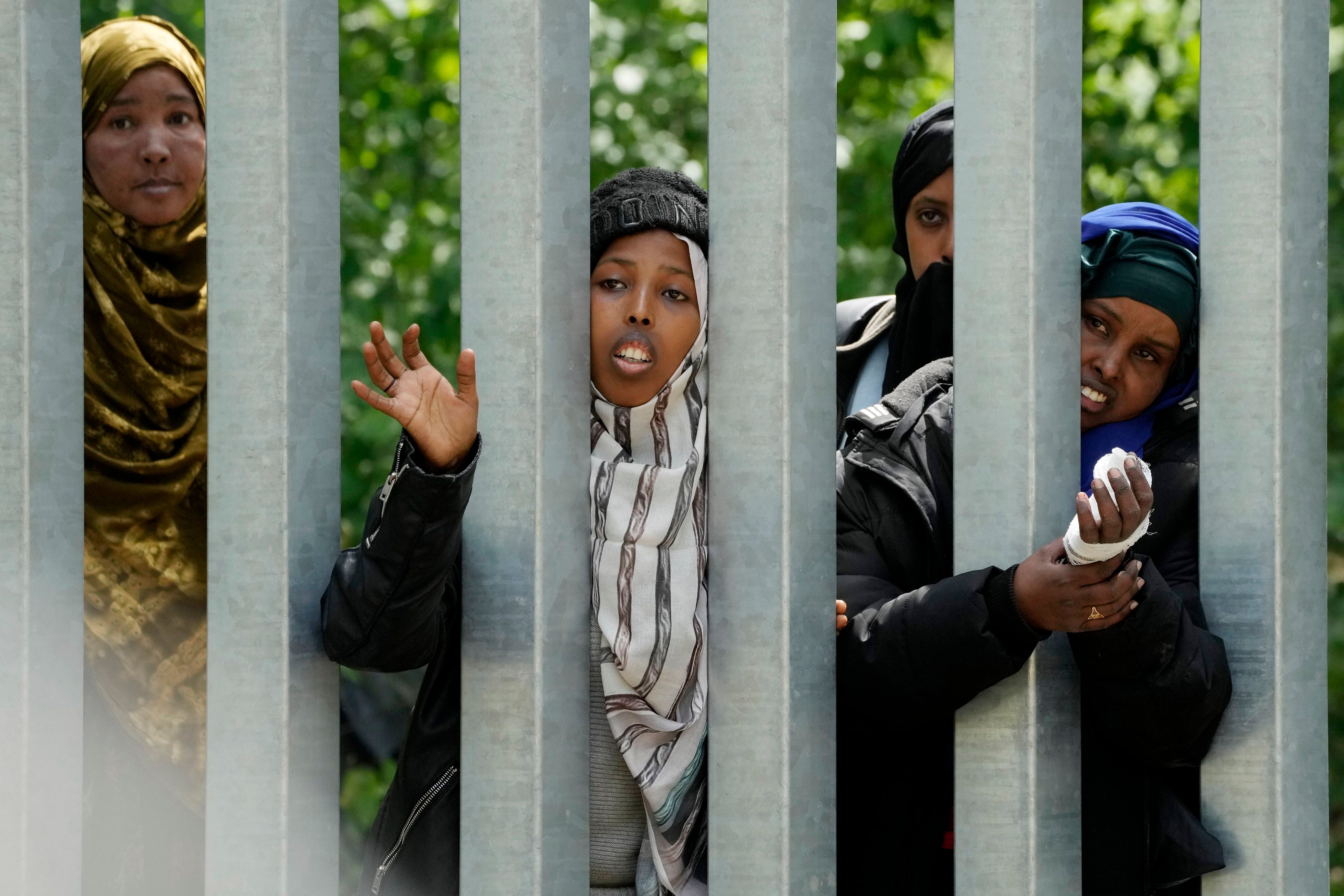 Un grupo de mujeres migrantes detrás de una cerca de metal trata de cruzar hacia Polonia, en el bosque de Bialowieza, en el este de Polonia, el miércoles 29 de mayo de 2024. (AP Foto/Czarek Sokolowski)