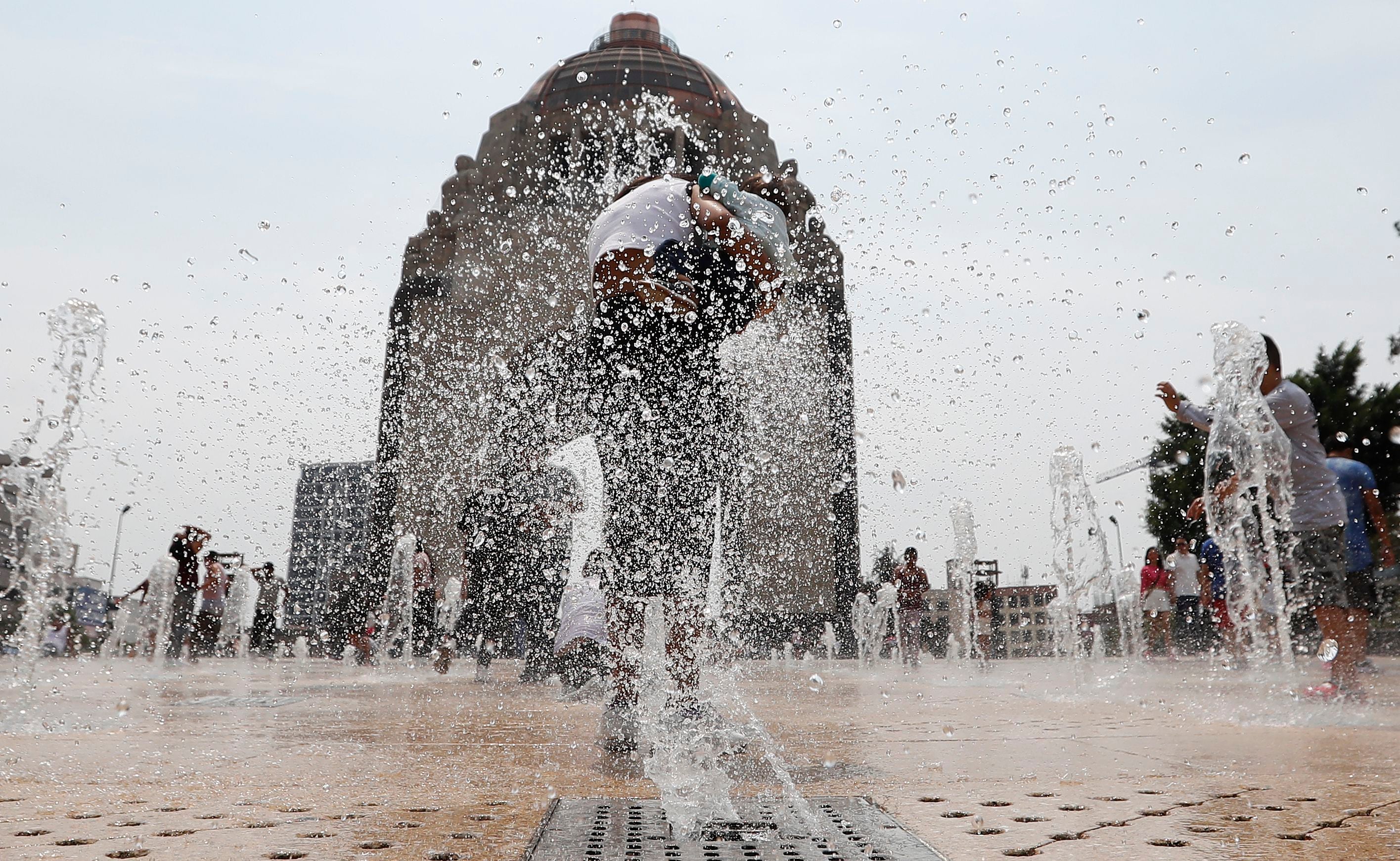 Personas se refrescan en una fuente del Monumento a la Revolución, en la Ciudad de México (México). Imagen de archivo. EFE/ Mario Guzmán
