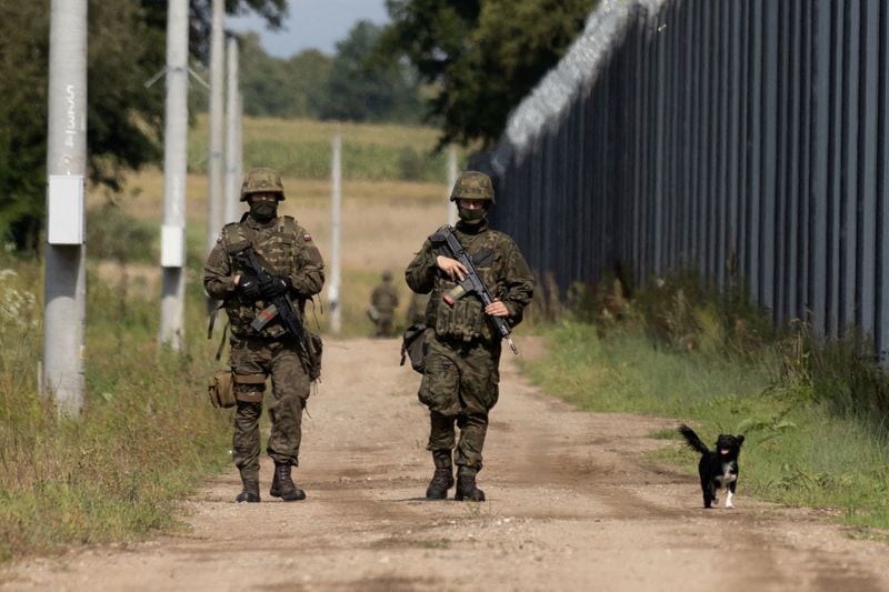 FOTO DE ARCHIVO: Soldados polacos y un perro local caminan a lo largo de la valla fronteriza en la frontera polaco-bielorrusa en Usnarz Gorny, Polonia. 30 de agosto de 2023. REUTERS/Kuba Stezycki