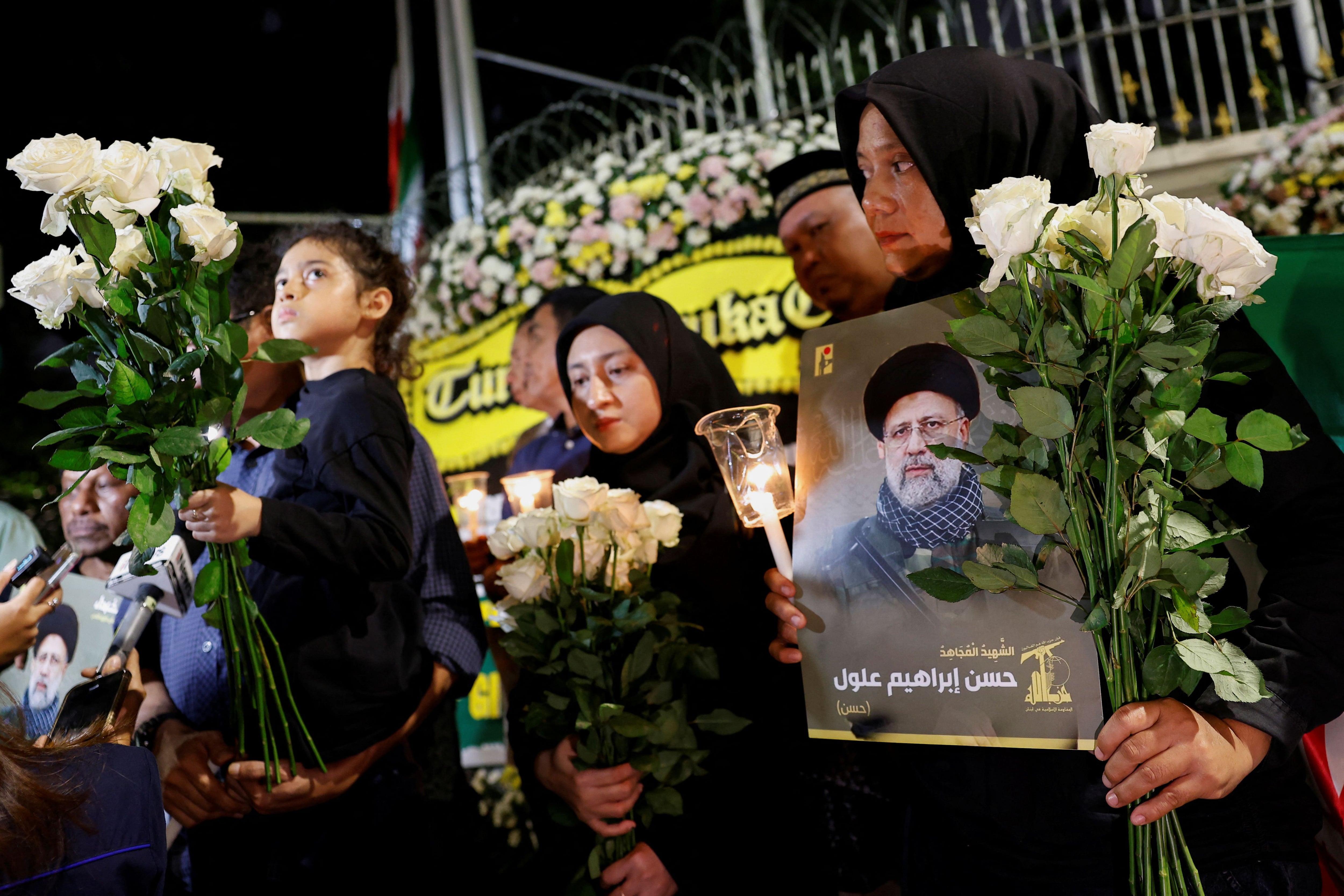 Personas con flores, velas y fotos del fallecido presidente iraní Ebrahim Raisi, asisten a una vigilia para rendirle homenaje a él y a otras víctimas en Yakarta, Indonesia (REUTERS/Willy Kurniawan)