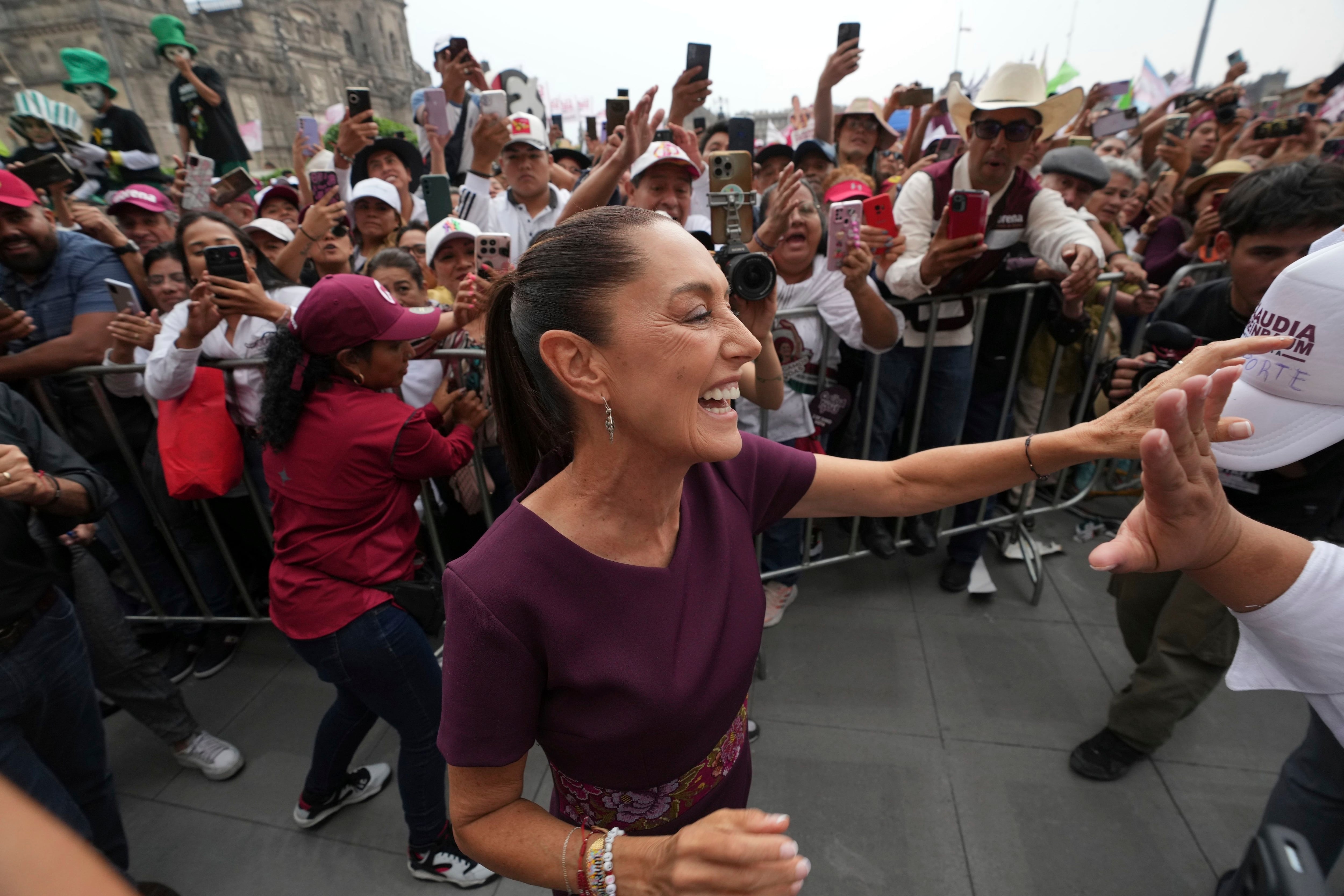 La candidata presidencial, Claudia Sheinbaum, arribó al Zócalo minutos después de las 16:00 horas. Mientras realizaba su recorrido para llegar al escenario, se detuvo para saludar a los asistentes y tomarse fotografías con ellos. (AP Foto/Eduardo Verdugo)