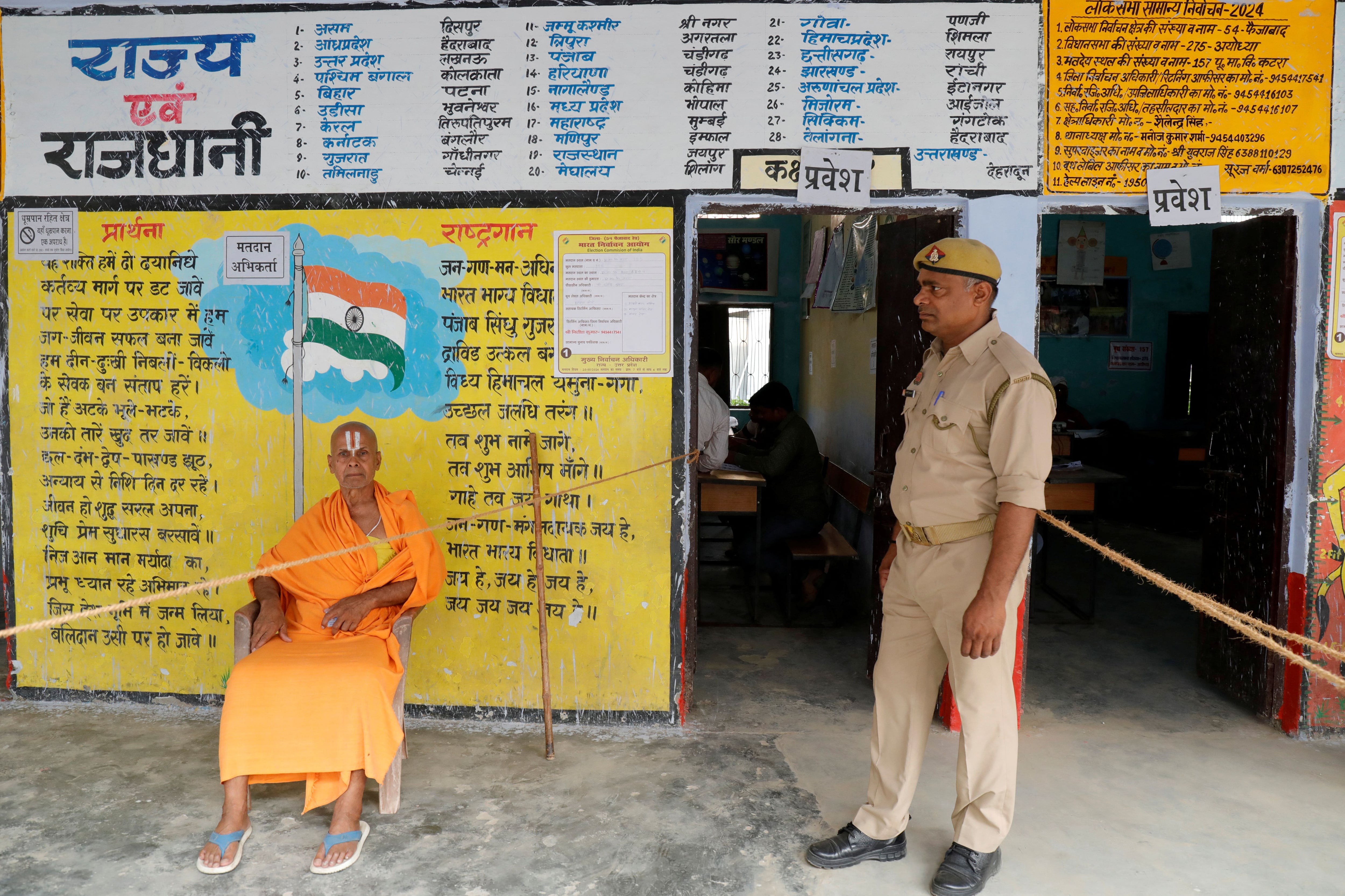 Un Sadhu o un santo hindú se sienta junto a un policía mientras espera para votar en una mesa electoral durante la quinta fase de las elecciones generales de la India, en Ayodhya, Uttar Pradesh, India, el 20 de mayo de 2024. REUTERS/Pawan Kumar