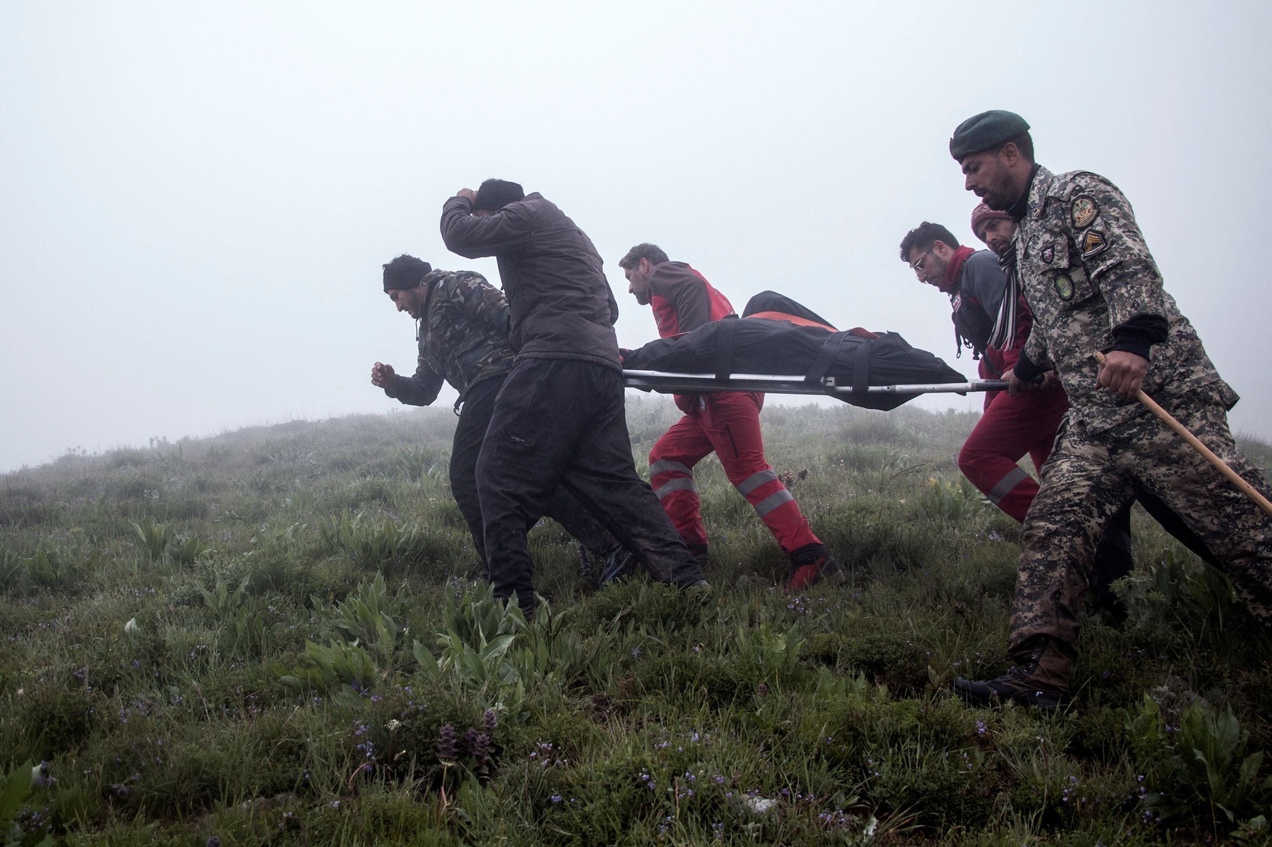 Un cuerpo es cargado por los rescatistas tras el hallazgo del helicóptero (REUTERS)