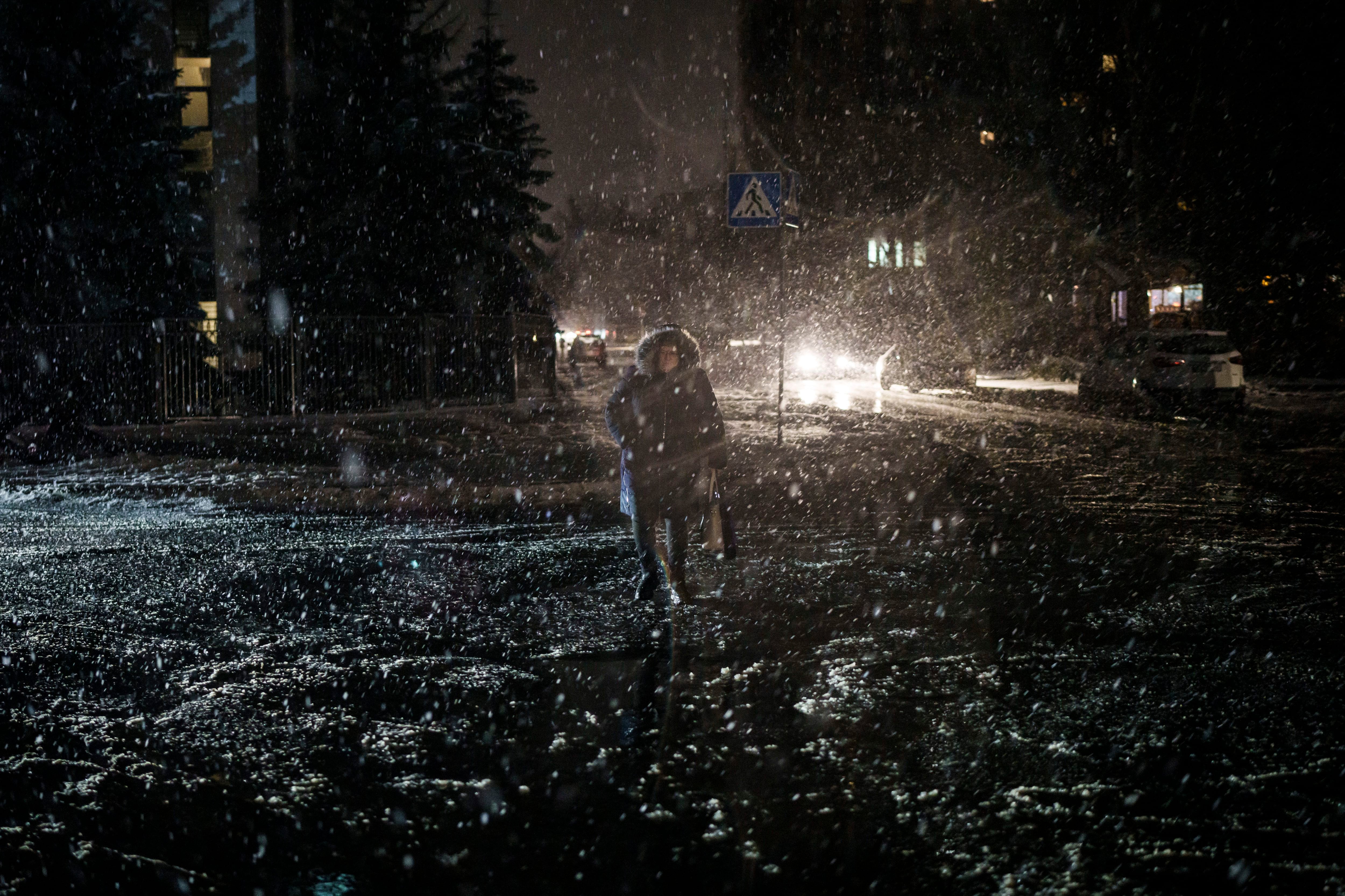 Una mujer cruza una calle durante una nevada, en pleno apagón en Kiev (AP Foto/Felipe Dana)