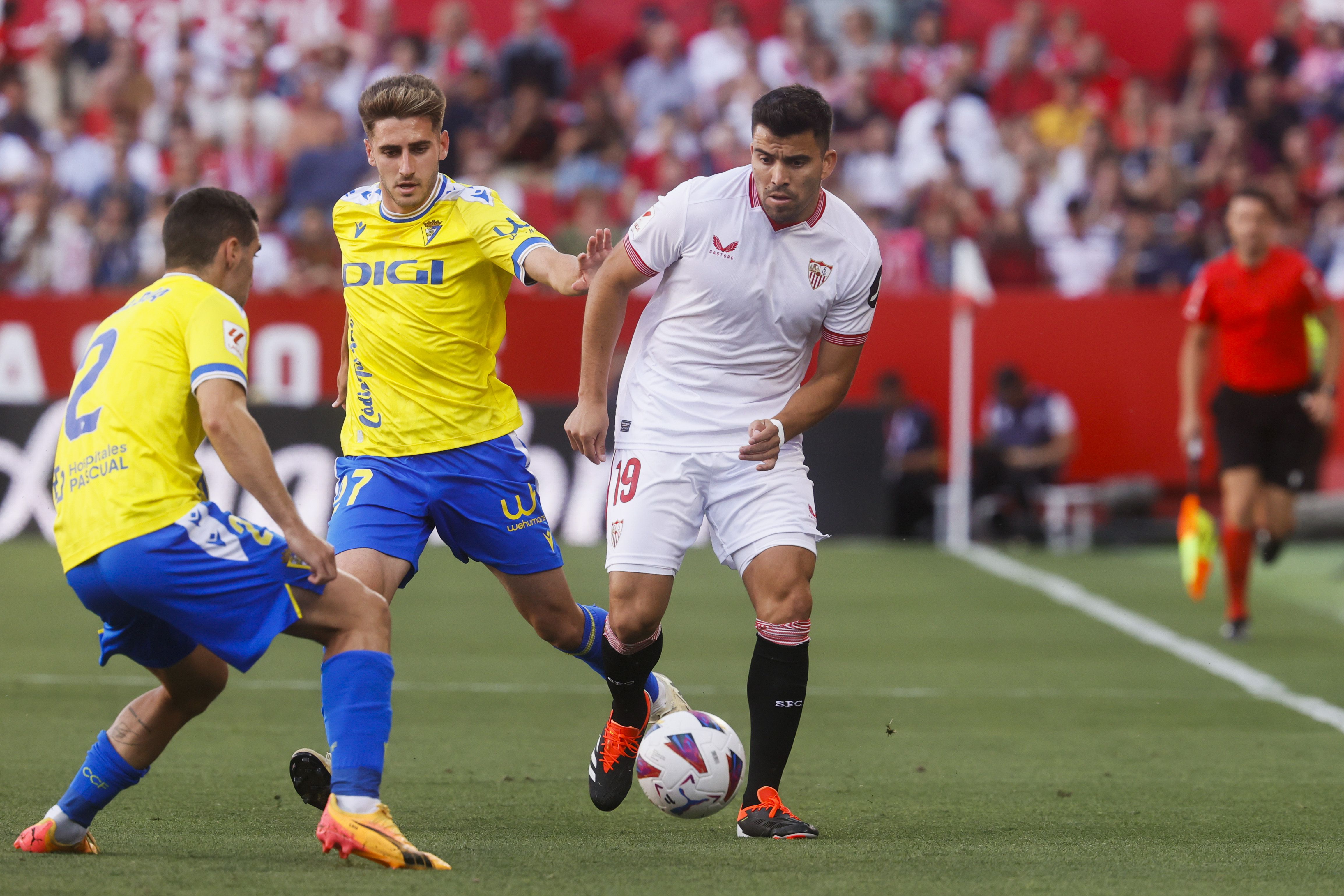 El centrocampista argentino del Sevilla Marcos Acuña (d), el defensa del Cádiz Joseba Zaldua (i) y su compañero Robert Navarro durante el partido de LaLiga disputado entre Sevilla y Cádiz, en el estadio Sanchez Pizjuan de Sevilla (EFE/José Manuel Vidal)
