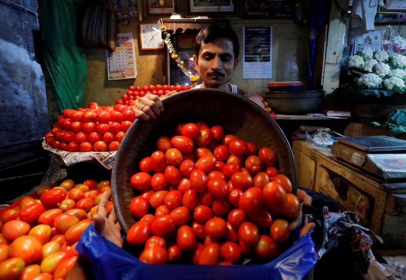 Un vendedor carga tomates en una bolsa para un cliente en un mercado mayorista de verduras en Bombay, India (Reuters)