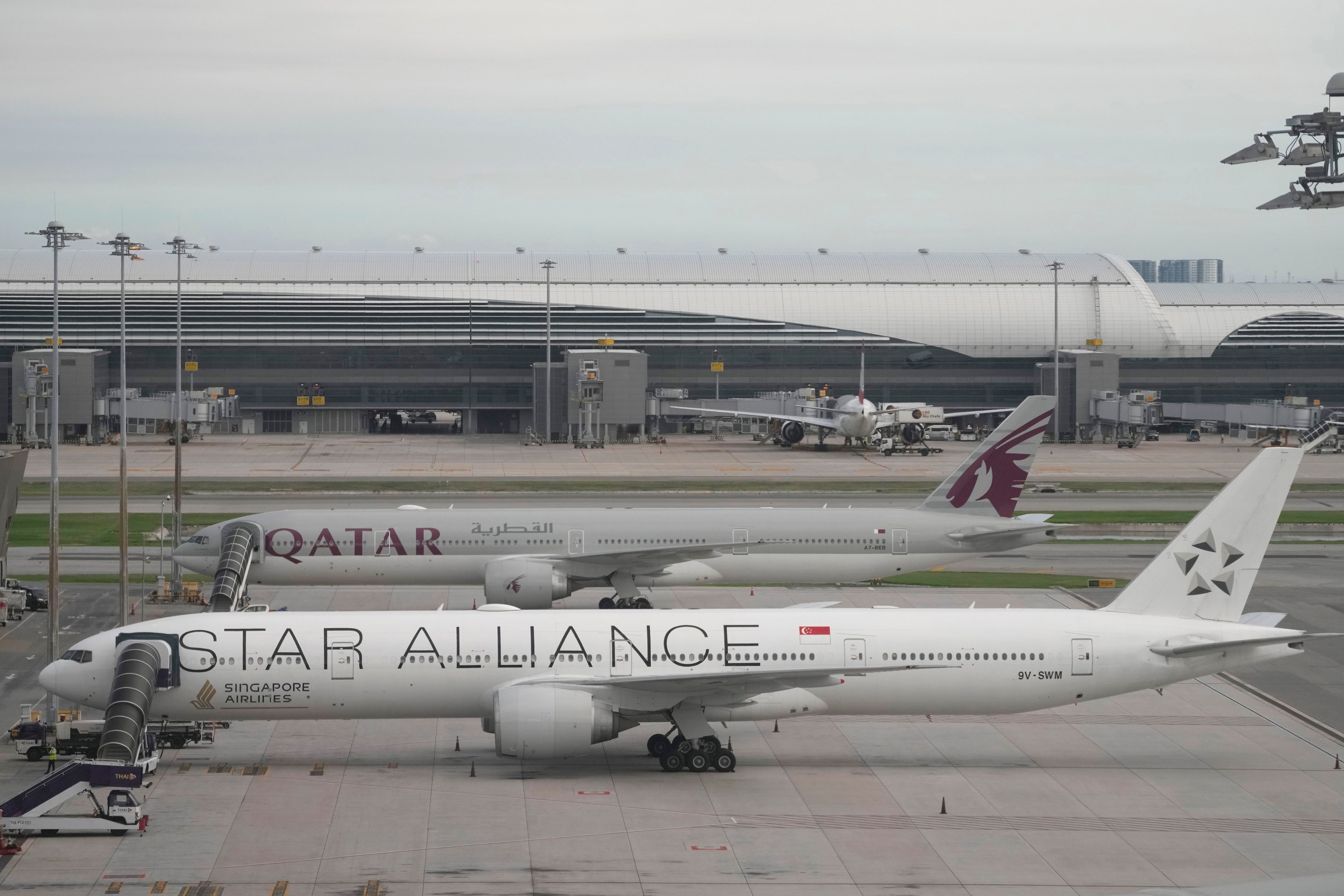 Un avión Boeing 777-300ER de Singapore Airlines, delante, se ve estacionado tras el vuelo SQ321 de Londres a Singapur que sufrió graves turbulencias, en el aeropuerto internacional de Suvarnabhumi, cerca de Bangkok, Tailandia, el miércoles 22 de mayo de 2024. Una persona murió y varias resultaron heridas en el incidente. (AP Foto/Sakchai Lalit)