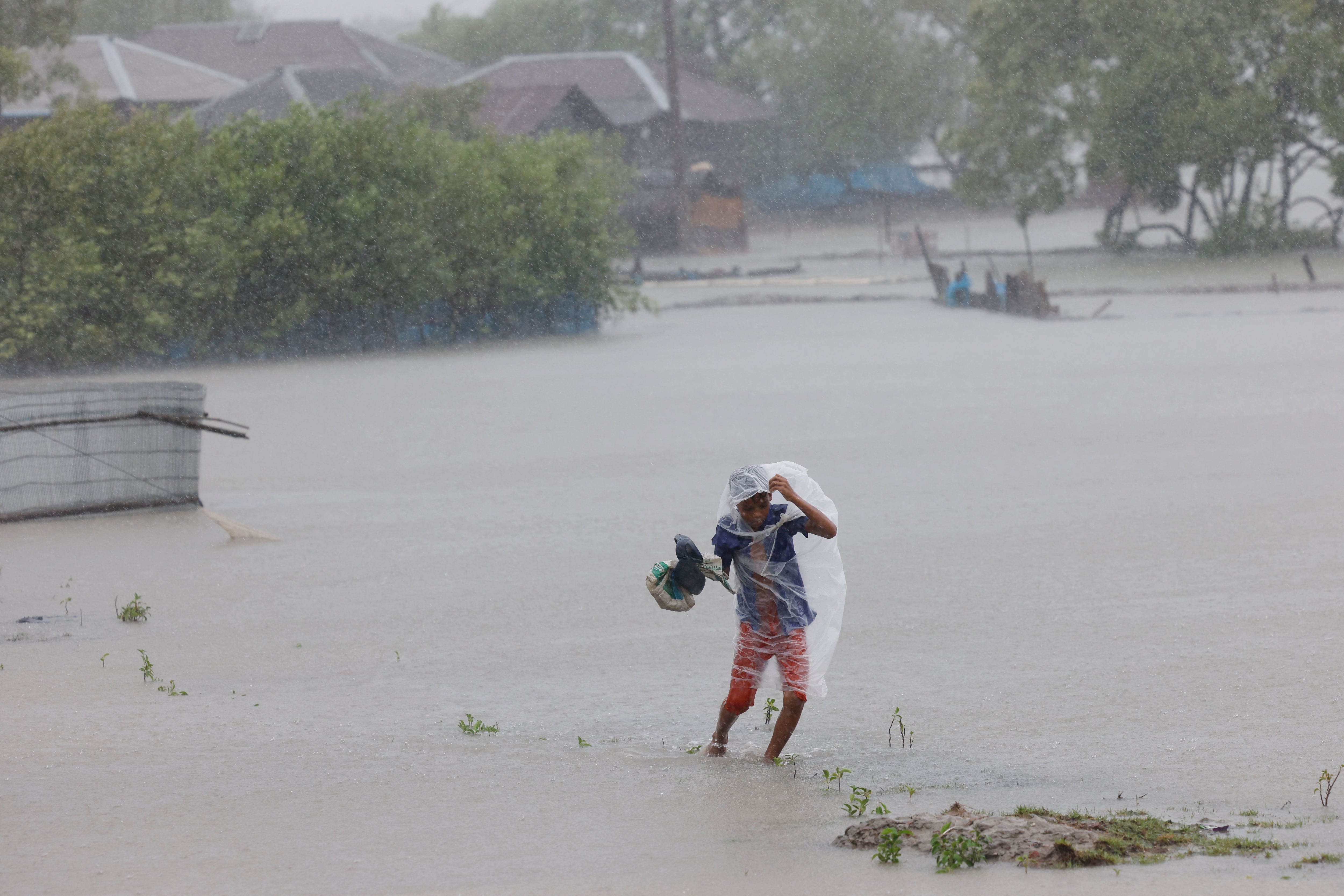 Un niño vadea el agua durante las fuertes lluvias que azotan el país a causa del ciclón Remal, en la zona de Shyamnagar, en Satkhira, Bangladesh (REUTERS/Mohammad Ponir Hossain)