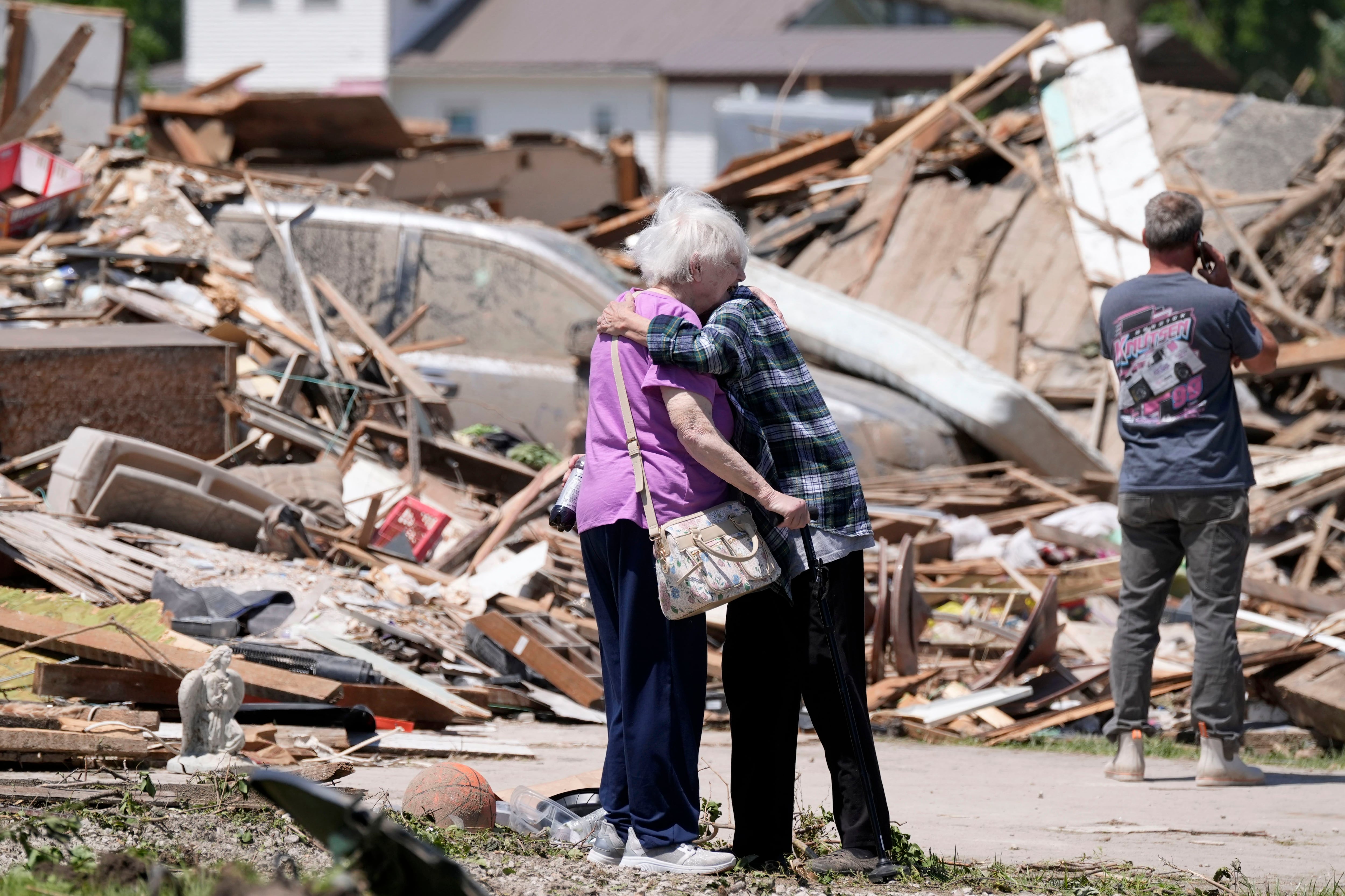 Dos mujeres se abrazan frente a sus casas, destrozadas por un tornado en Greenfield, Iowa. (AP Foto/Charlie Neibergall)