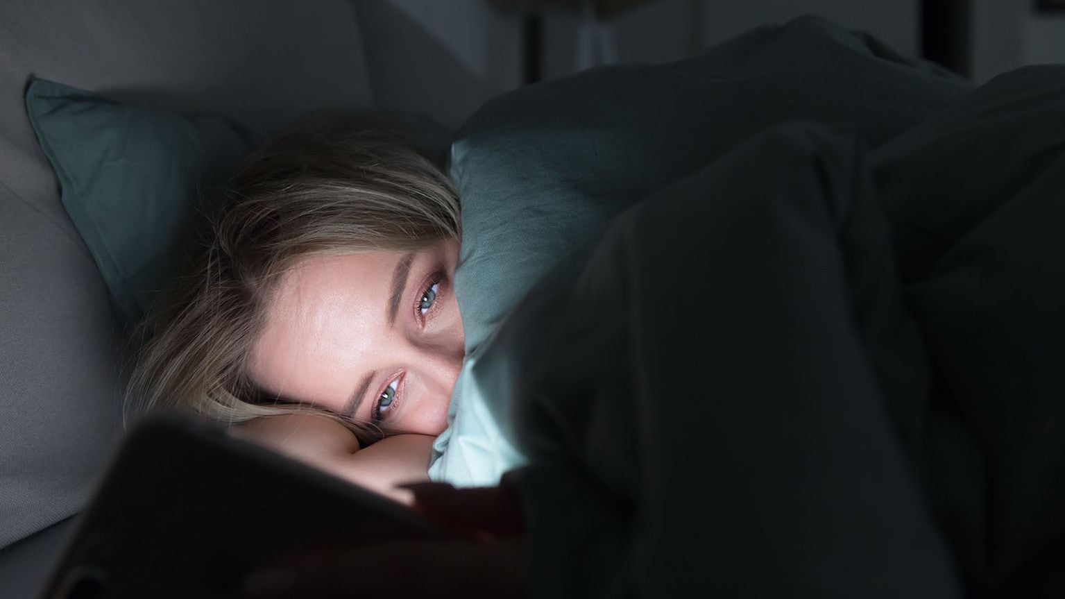 Una joven mira su móvil antes de dormir (Shutterstock)