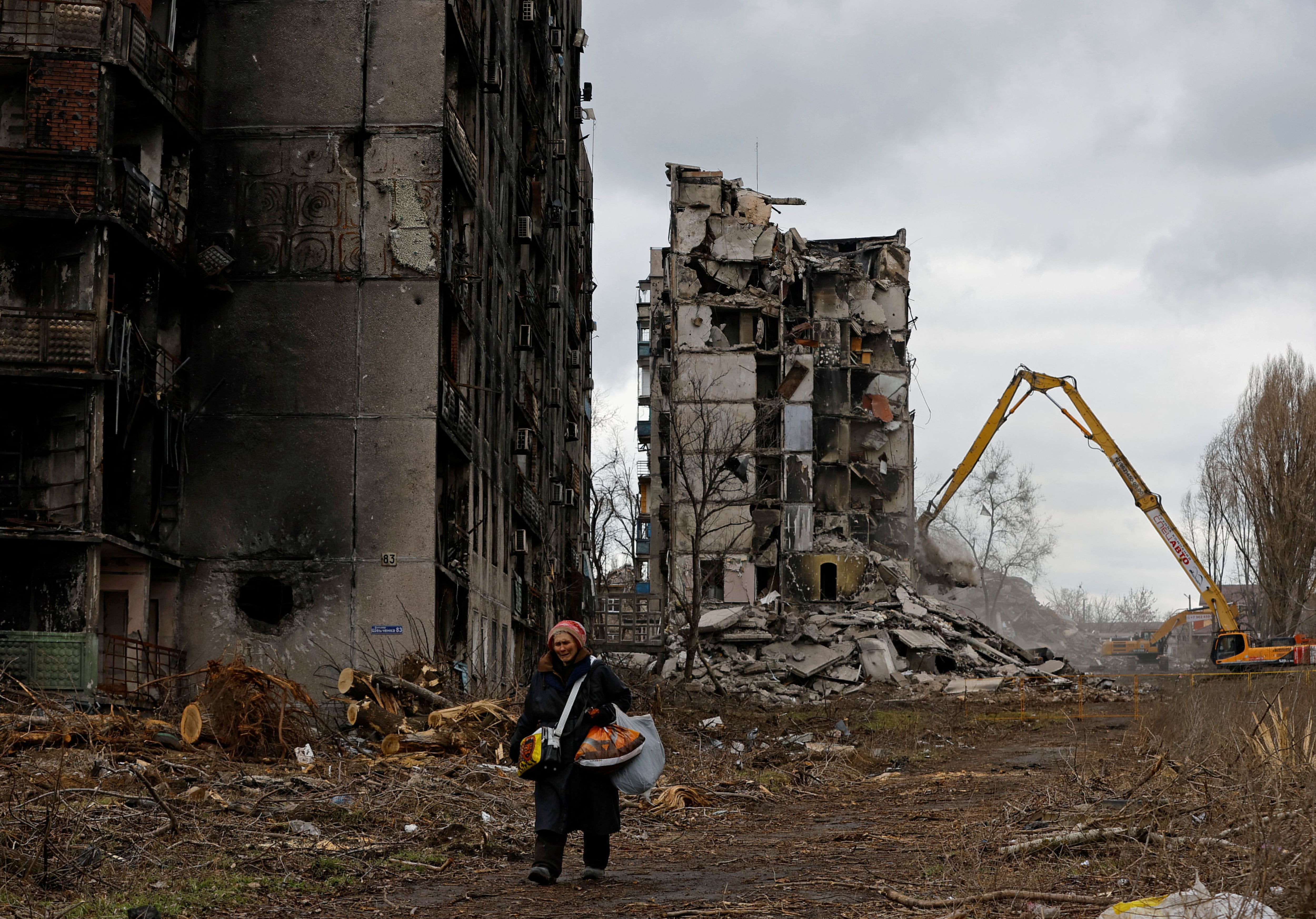 Una mujer camina por su barrio frente a los bloques de apartamentos destruidos en Mariupol, la ciudad símbolo de la brutalidad rusa en el este de Ucrania (REUTERS/Alexander Ermochenko)