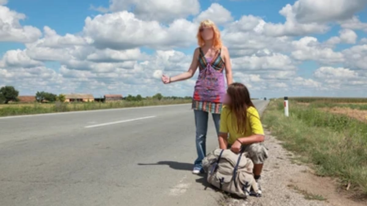 Mujer pidiendo un aventón en carretera