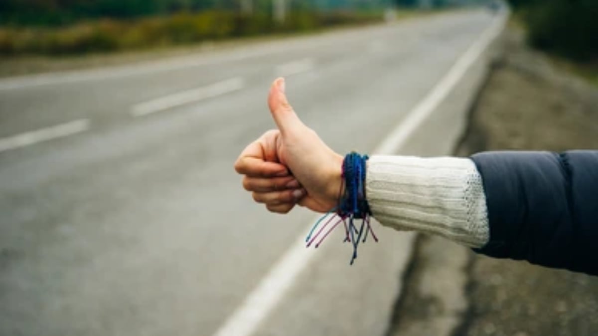 Mujer pidiendo un aventón en carretera