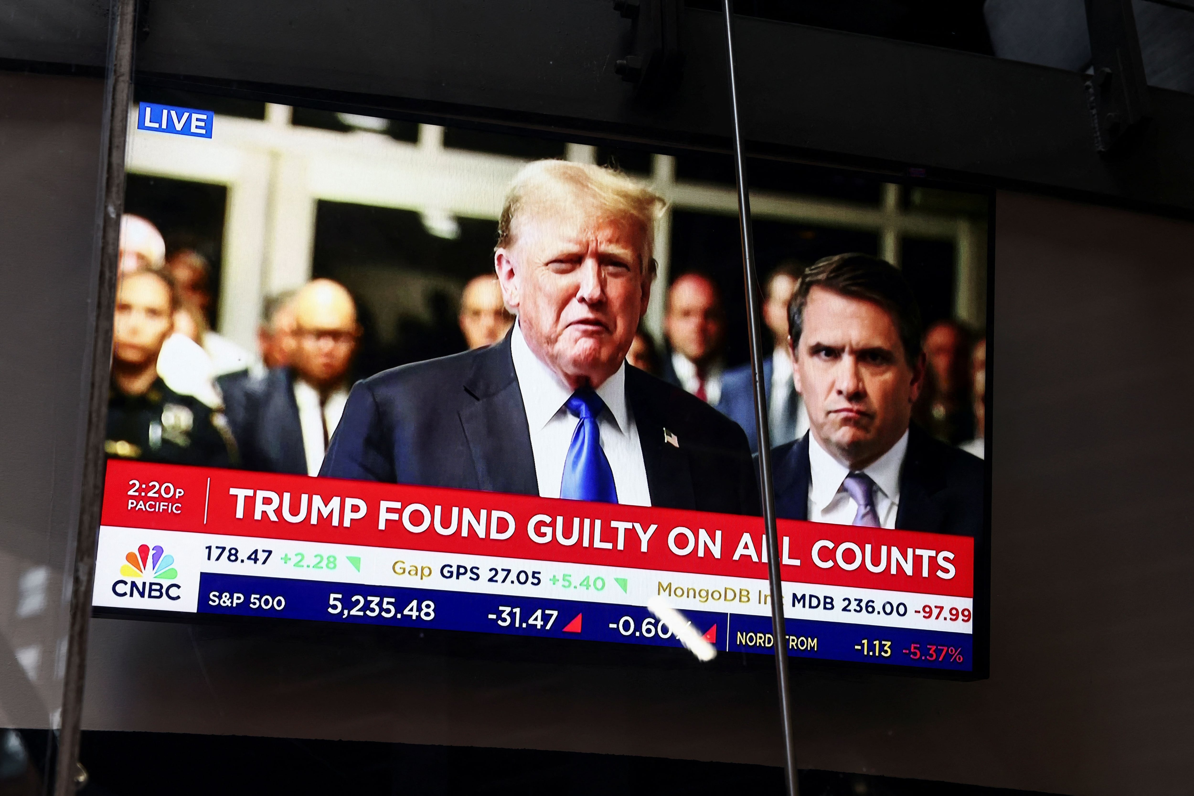 Una pantalla de televisión en el Nasdaq MarketSite muestra la noticia del veredicto en el juicio penal del ex presidente estadounidense Donald Trump por cargos de falsificar registros comerciales para ocultar dinero pagado para silenciar a la estrella porno Stormy Daniels en 2016, en la ciudad de Nueva York, Estados Unidos, el 30 de mayo. 2024. REUTERS/Andrew Kelly