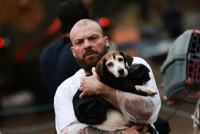 Un voluntario lleva un perro que ha sido rescatado de una zona inundada en Porto Alegre (REUTERS/Diego Vara)