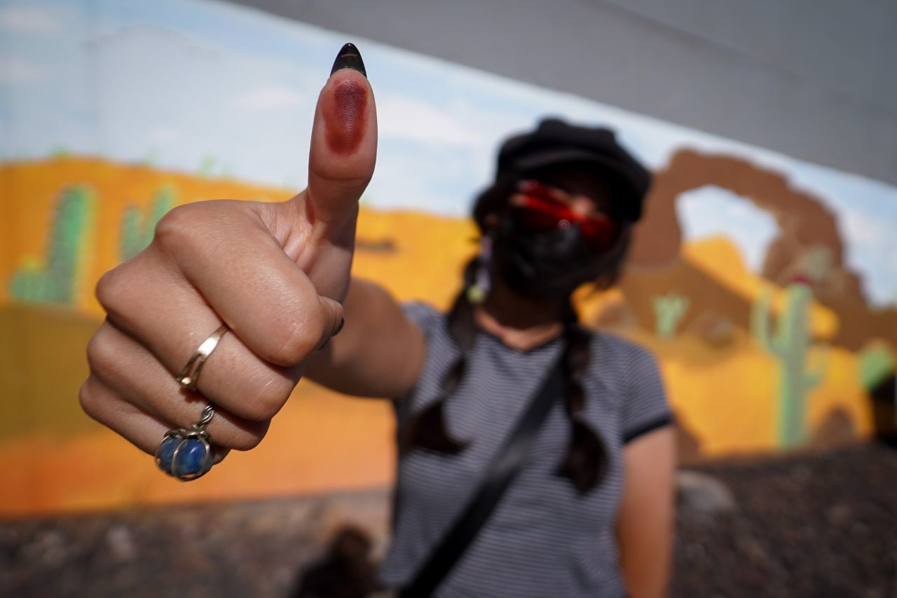 Una ciudadana muestra su pulgar con tinta indeleble tras emitir su voto