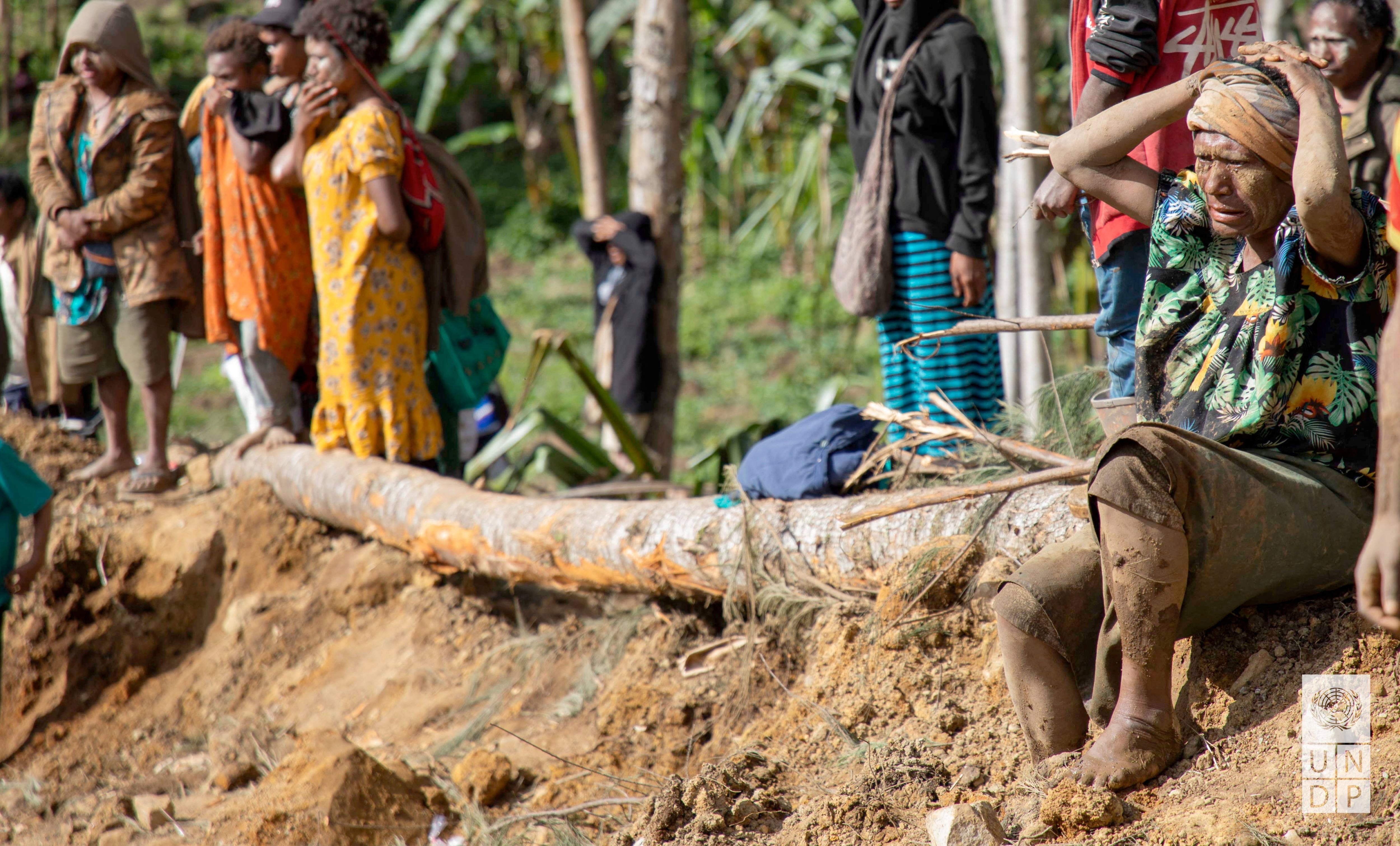 Aldeanos se toman un descanso en medio de sus esfuerzos por remover el barro que se ha acumulado sobre sus casa (UNDP Papua New Guinea/Handout via REUTERS)