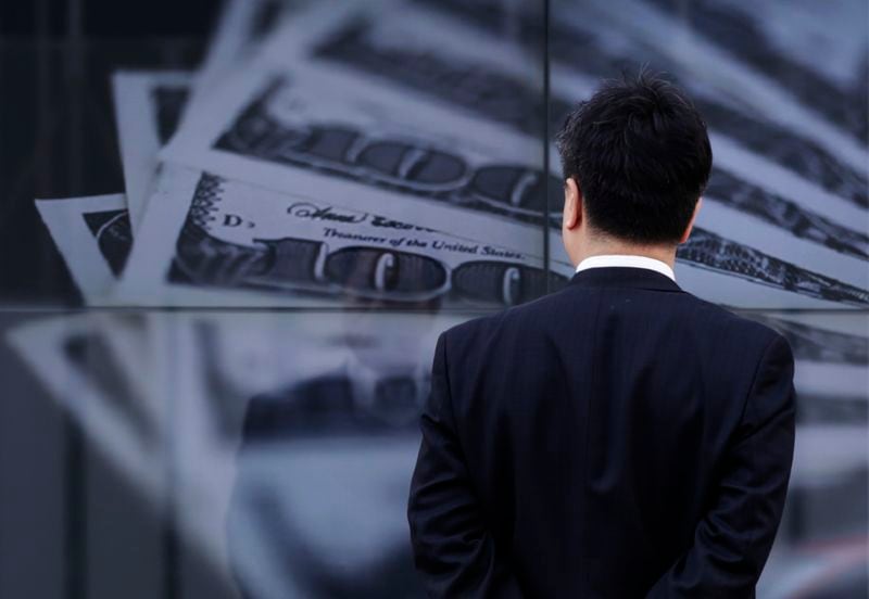 FOTO DE ARCHIVO: Un hombre de negocios mira una pantalla que muestra una foto de billetes de 100 dólares estadounidenses. 2013. (REUTERS/Toru Hanai)