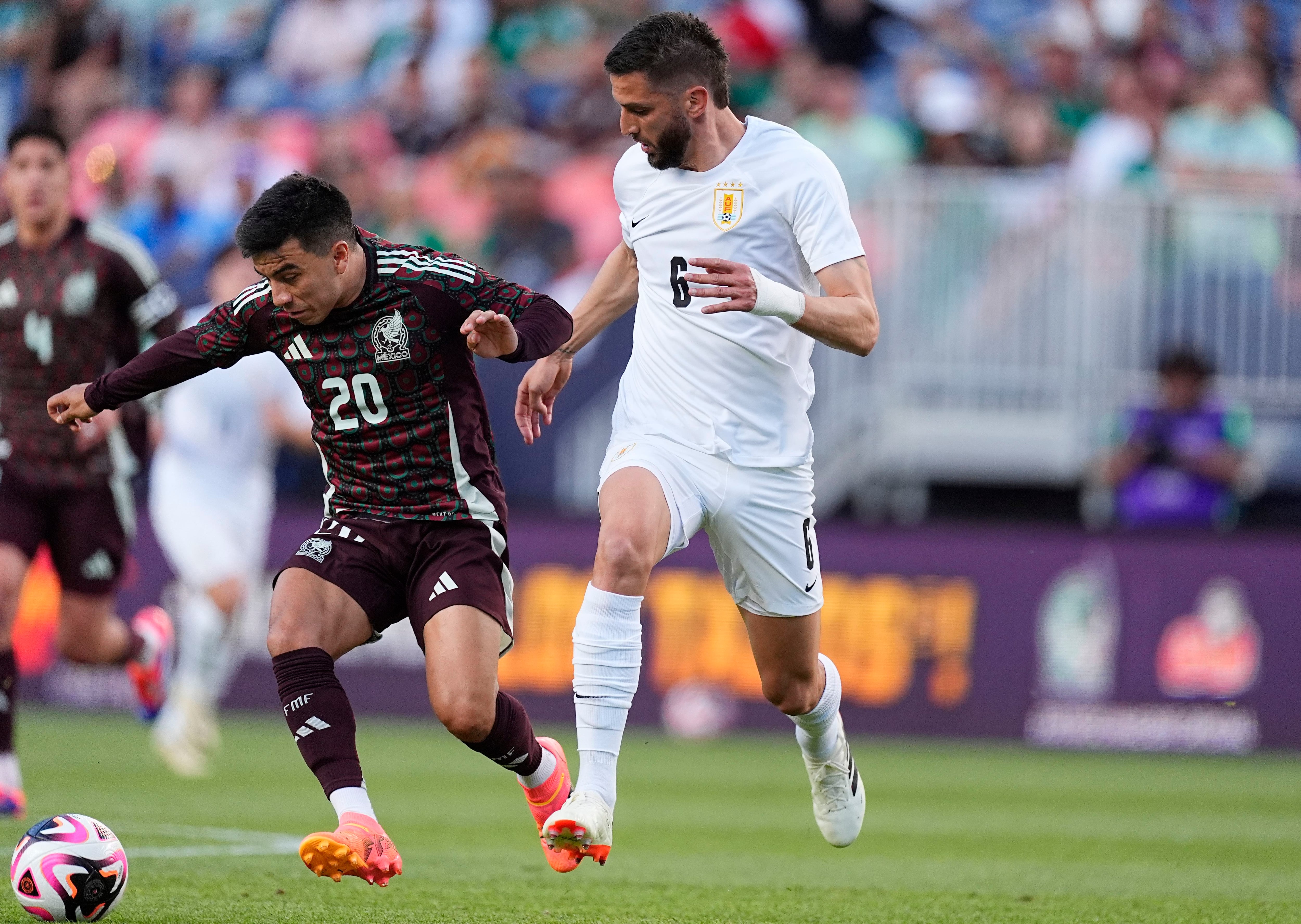 El volante mexicano Fernando Beltrán (izquierda) pugna por el balón con el volante uruguayo Rodrigo Bentancur durante el primer tiempo del partido amistoso rumbo a la Copa América, el miércoles 5 de junio de 2024, en Denver. (AP Foto/David Zalubowski)